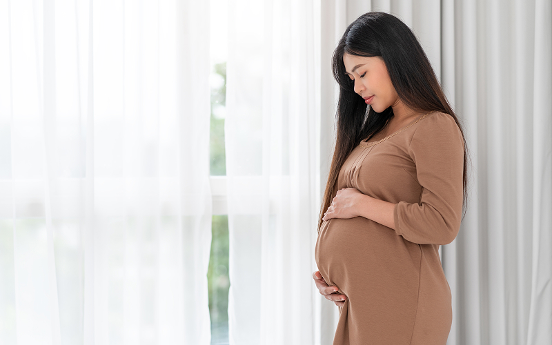 Pregnant woman holding belly before starting postpartum recovery journey.
