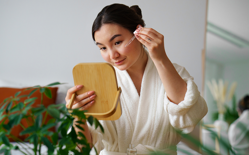 Woman applying facial serum to treat a damaged skin barrier.