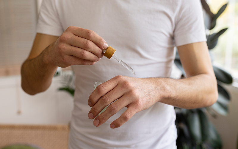 Close-up of man applying skincare serum to his hand.