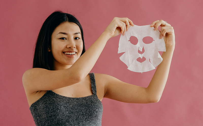 Woman holding up hydrating sheet mask for skincare routine