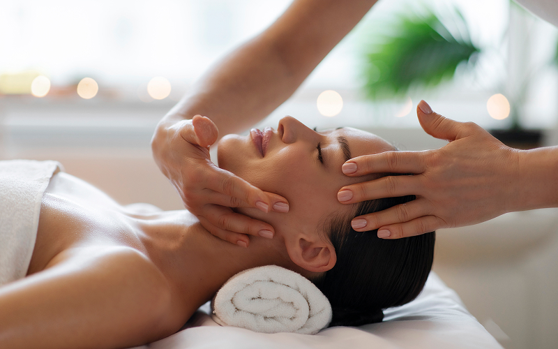 Woman receiving relaxing facial massage treatment at spa clini